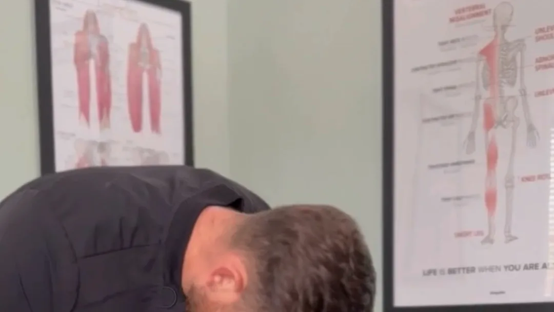 A Spinal Solutions chiropractor treating a patient, anatomy charts on the treatment room wall